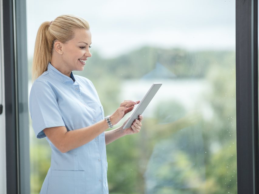 A nurse reading a tablet by a window
